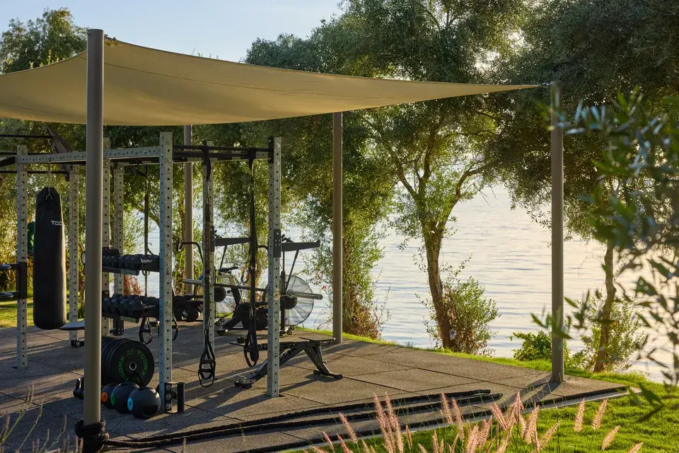 Avali - An outdoor fitness area with exercise equipment under the trees, right by the ocean.