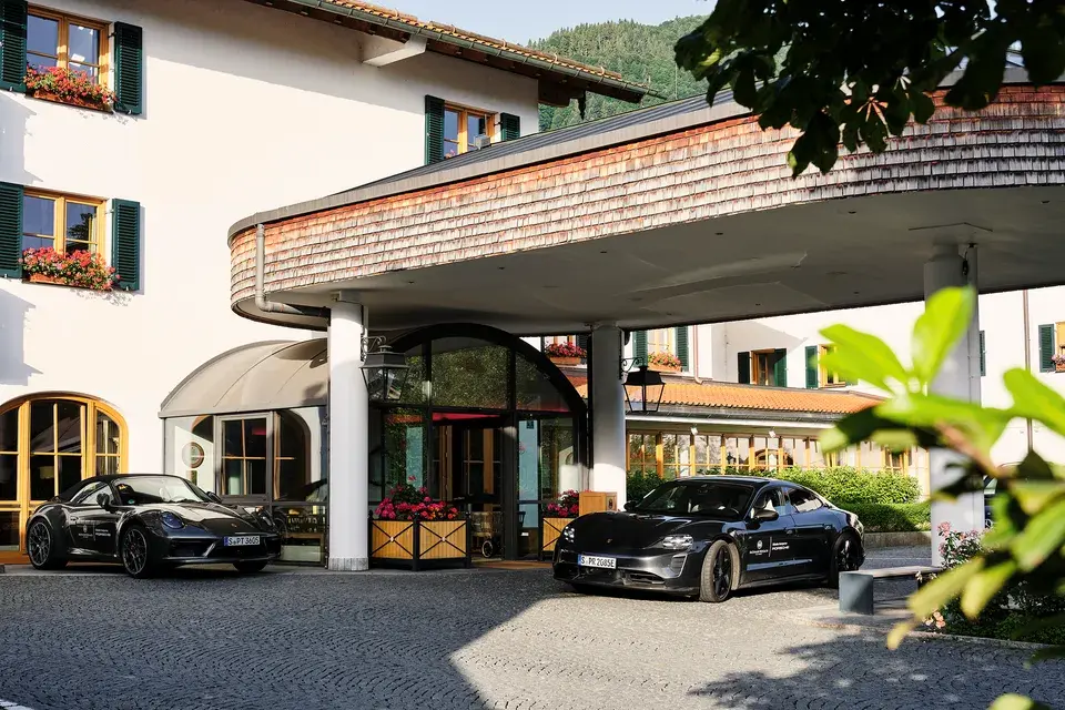 The covered entrance area of the Bachmair Weissach Spa & Resort, with a vehicle parked in front of the hotel.