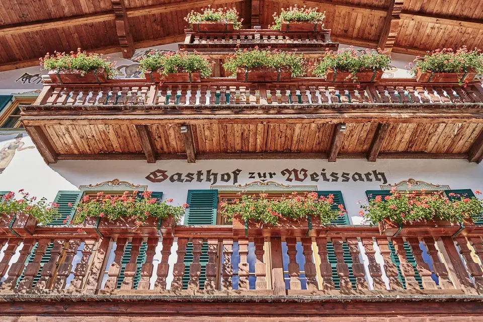 Exterior of Gasthof zur Weissach with wooden balconies, green shutters, and flower boxes.