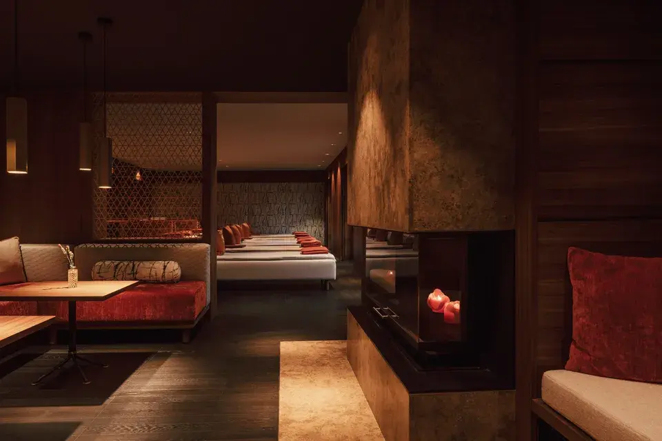 Relaxation area at the Bachmair Weissach MIZU ONSEN SPA with dark wood, cushioned loungers, and Japanese-inspired design elements.