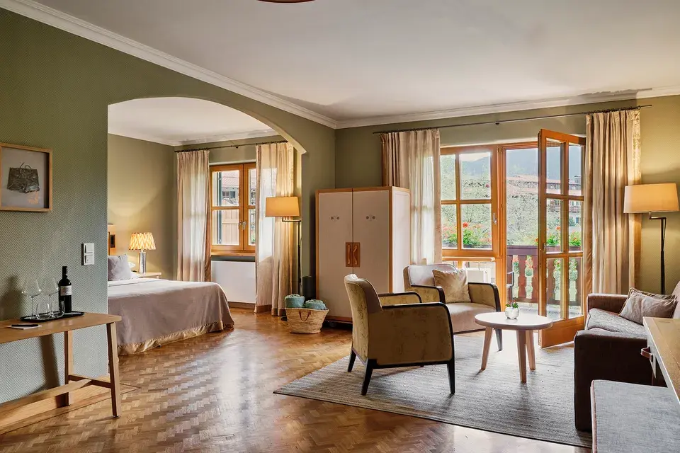 Junior Suite at the Bachmair Weissach Spa & Resort, featuring hardwood floors, a seating area, and doors that open onto the balcony.