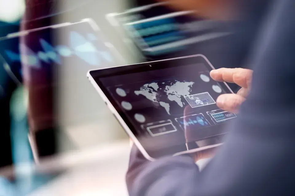 Person nutzt ein Tablet mit einer digitalen Weltkarte
