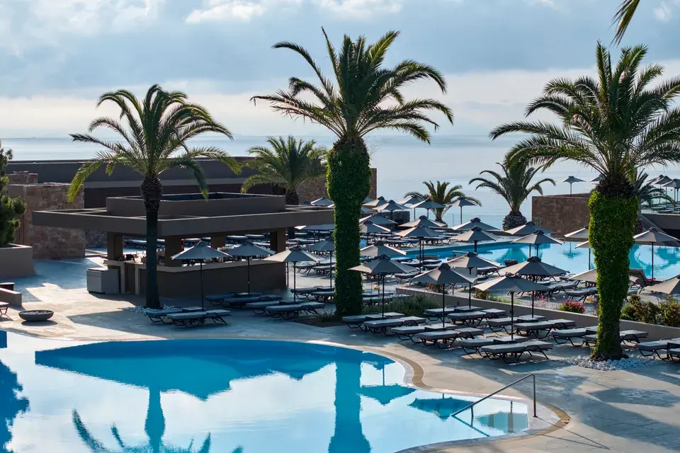 Pool area at MarBella in Corfu with palm trees overlooking the Ionian Sea.
