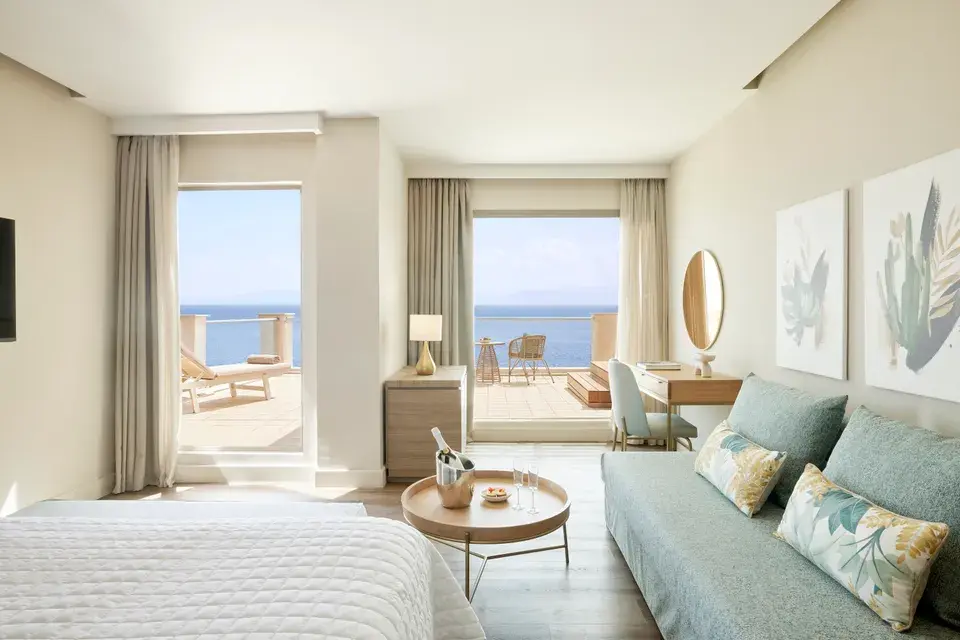 MarBella Junior Suite Grand Terrace: Jacuzzi with a bed, a seating area, and large glass doors leading to a terrace with an ocean view.
