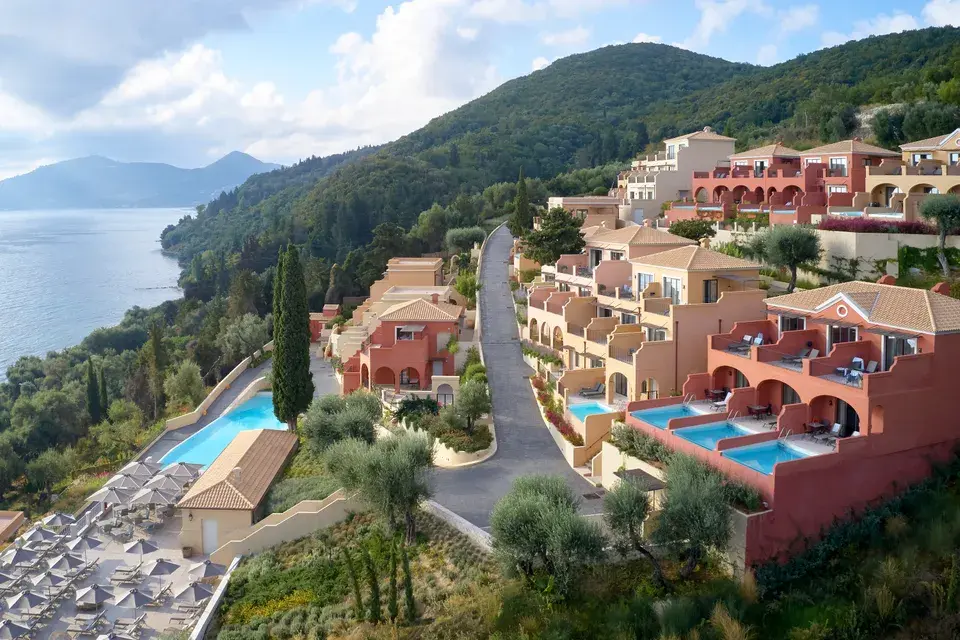 Terraced Nido resort in Corfu with pools on a wooded hillside overlooking the Ionian Sea.