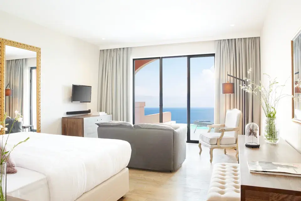 Nido - Deluxe Junior Suite with Private Pool: A bright hotel room with a bed and large windows overlooking the ocean.