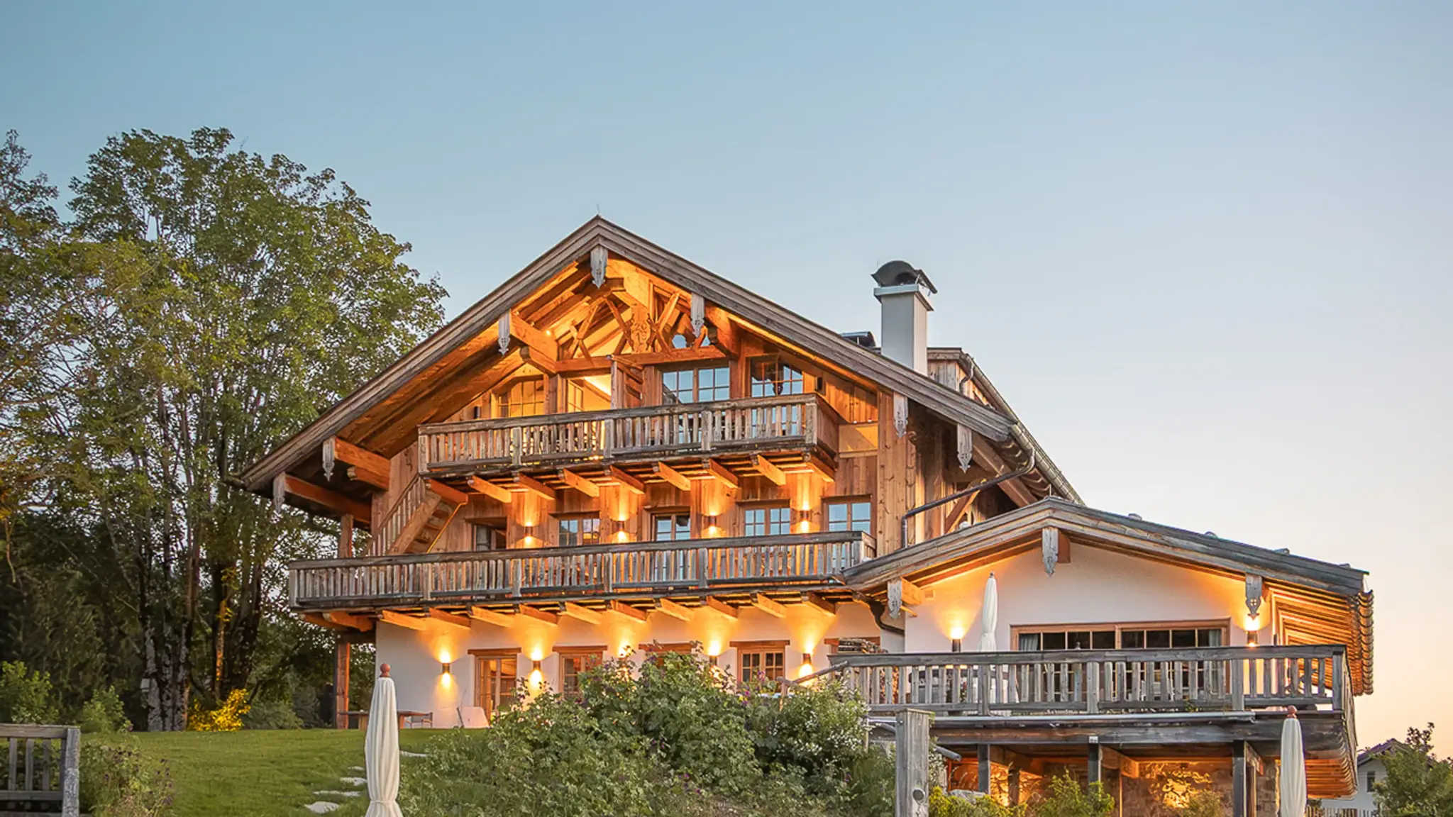 Chiemsee Chalet Hotelansicht von außen mit See im Hintergrund und stimmungsvoller Beleuchtung