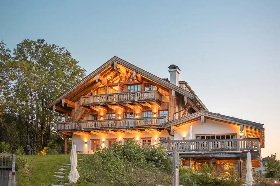 Chiemsee Chalet Hotelansicht von außen mit See im Hintergrund und stimmungsvoller Beleuchtung