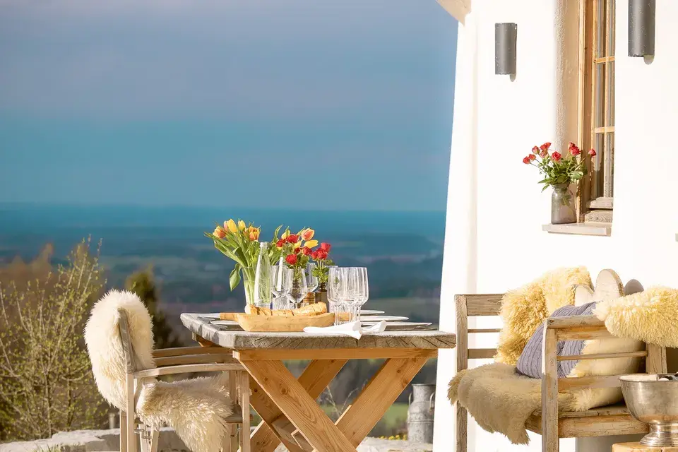 Set table with flowers and glasses on a terrace overlooking the lake.