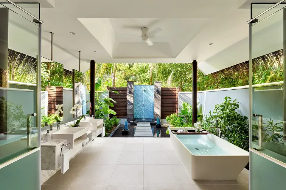Spacious bathroom in the Beach Pool Villa at Niyama Private Islands Maldives, featuring a freestanding bathtub, double sinks, and an unobstructed view of the tropical vegetation.