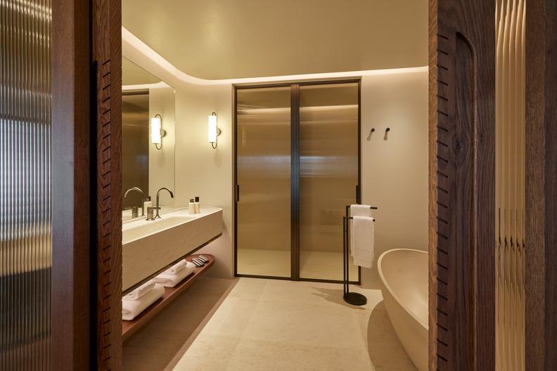 Modern bathroom at Daios Cove with a long vanity, bathtub, and glass-enclosed shower area.
