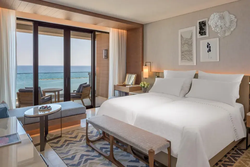 Deluxe Twin Bedroom mit Doppelbett, Sitzecke und bodentiefen Fenstern mit Blick auf das Meer