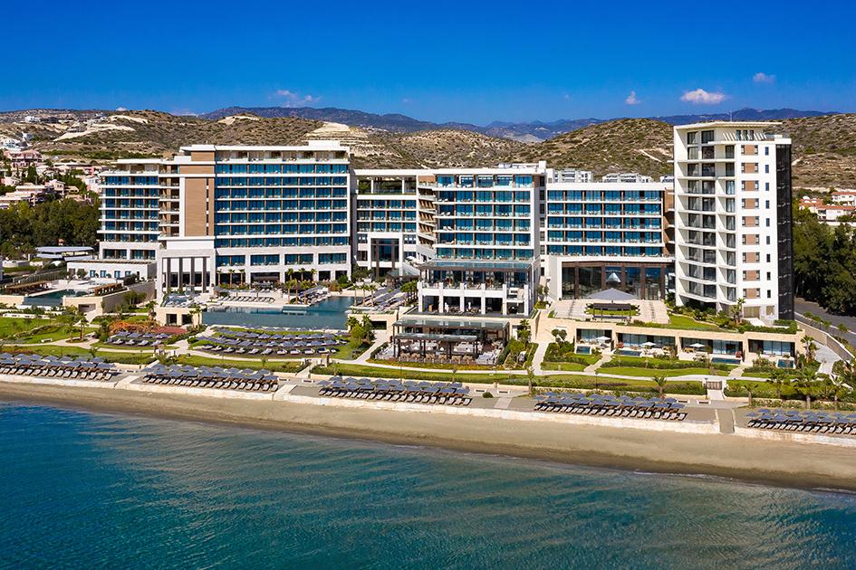 Außenansicht des AMARA auf Zypern mit Hotelgebäude, Poolanlage und Mittelmeer im Vordergrund