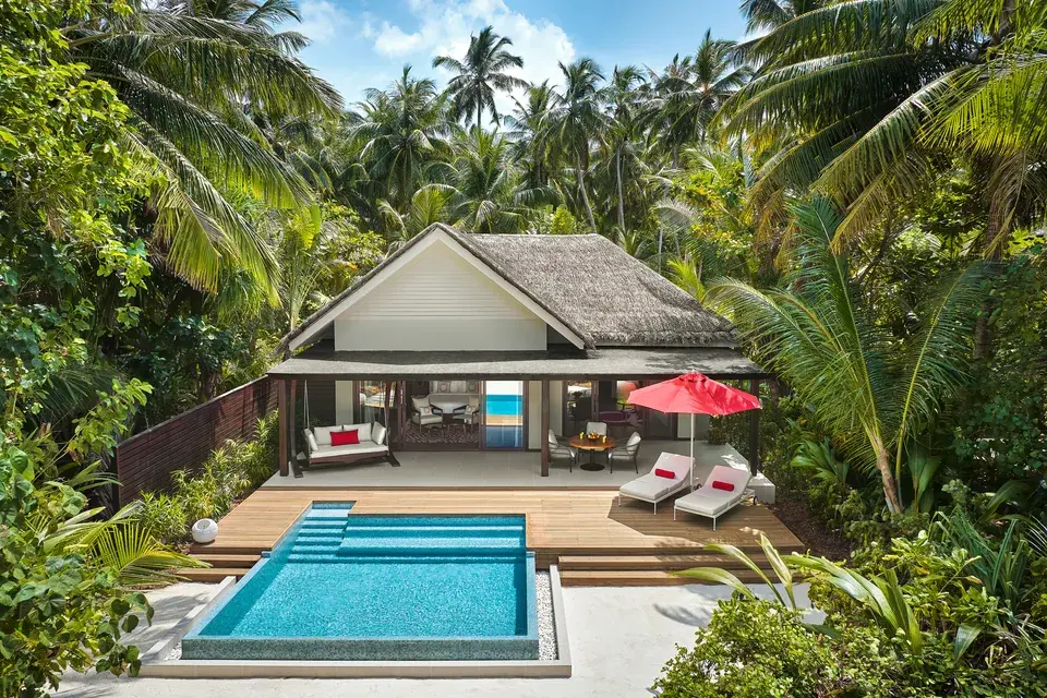 Family Beach Villa at Niyama Private Islands Maldives, surrounded by palm trees and tropical vegetation, with a covered terrace in front of the entrance