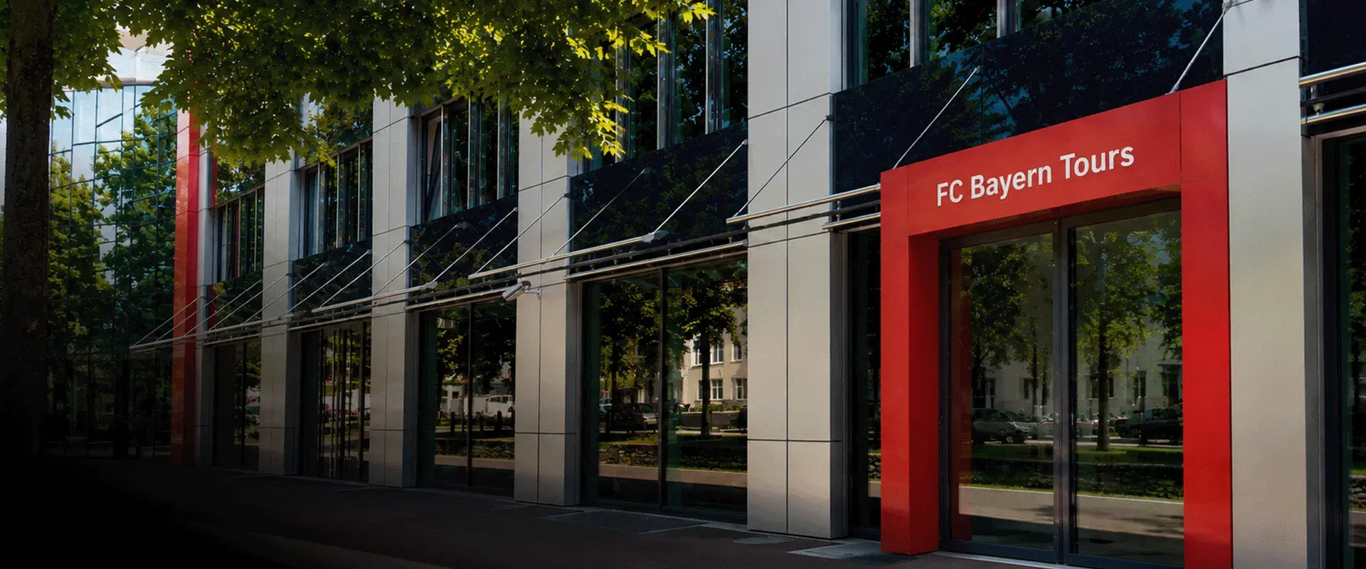 Außenansicht des FC Bayern Tours Büros mit dem rot eingefassten und beschrifteten Eingangsbereich.
