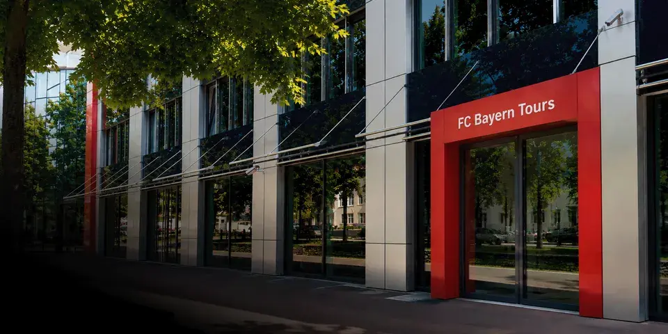Außenansicht des FC Bayern Tours Büros mit dem rot eingefassten und beschrifteten Eingangsbereich.