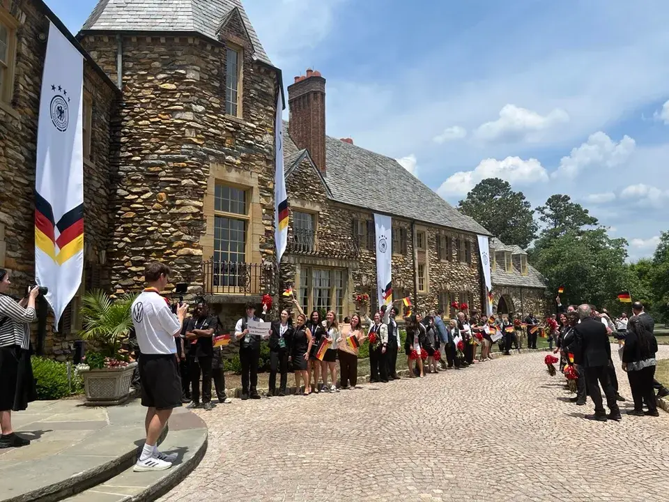 Team Base Camp Granlyn Estate USA, Mitarbeiter stehen in Reihe mit Deutschlandfahne für den Empfang