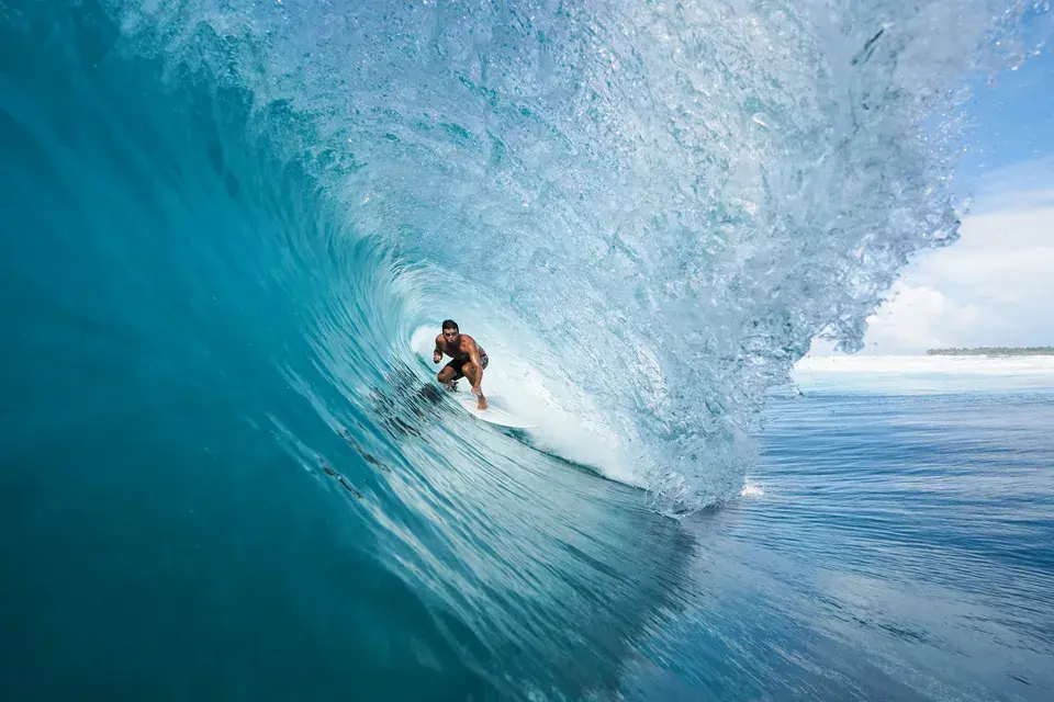 Surfer riding inside a large breaking wave in the turquoise waters off Niyama Private Islands Maldives.