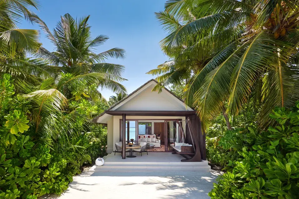 Beach villa at Niyama Private Islands Maldives with a private pool, wooden terrace, lounge chairs, and lush tropical vegetation.