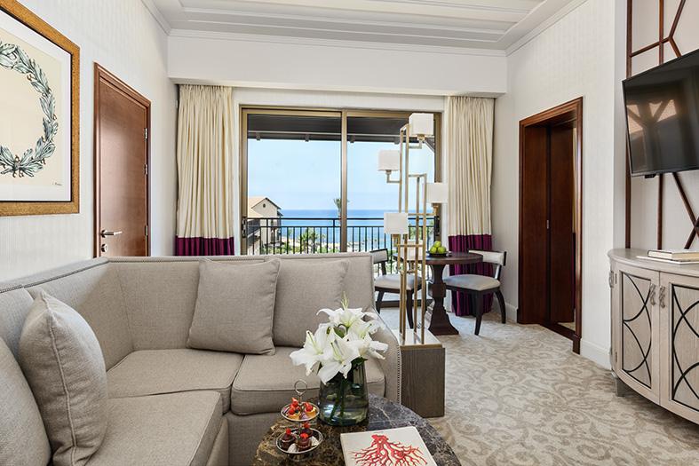 Elysium Junior Suite: Bright living area with a sofa and a balcony with a view of the sea