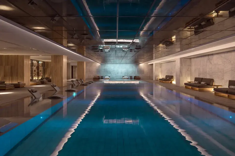 Innenpool im Spa des AMARA mit Liegen und beleuchteten Sitzbereichen entlang des Pools