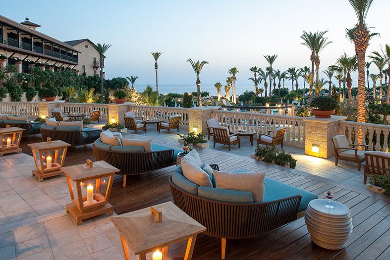 Sun terrace with lounge chairs and seating areas, offering a view of the sea at dusk