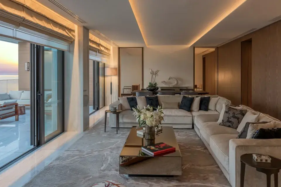 The Amara Suite - Großzügiger Wohnbereich mit Sofa, Esstisch und bodentiefen Fenstern