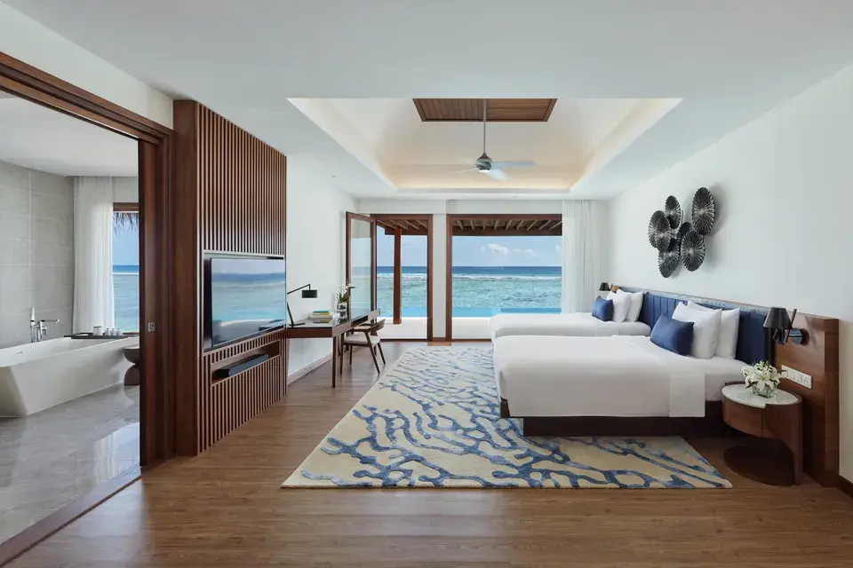 Spacious bedroom in the Ocean Pool Villa at Niyama Private Islands Maldives, featuring a double bed and floor-to-ceiling doors opening onto the turquoise sea.