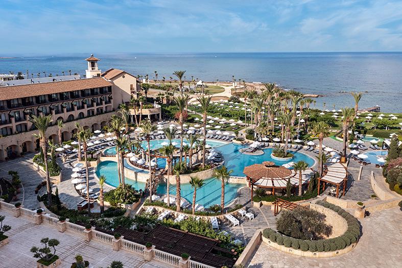 Elysium in Paphos mit weitläufiger Poolanlage, Palmen und Blick auf das Mittelmeer