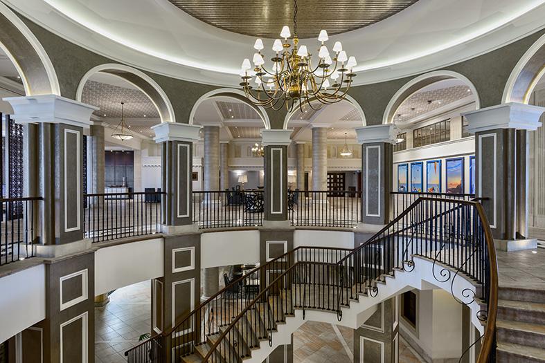 Staircase at the Elysium featuring a lobby with marble and a chandelier, dark banisters, and classic interior design